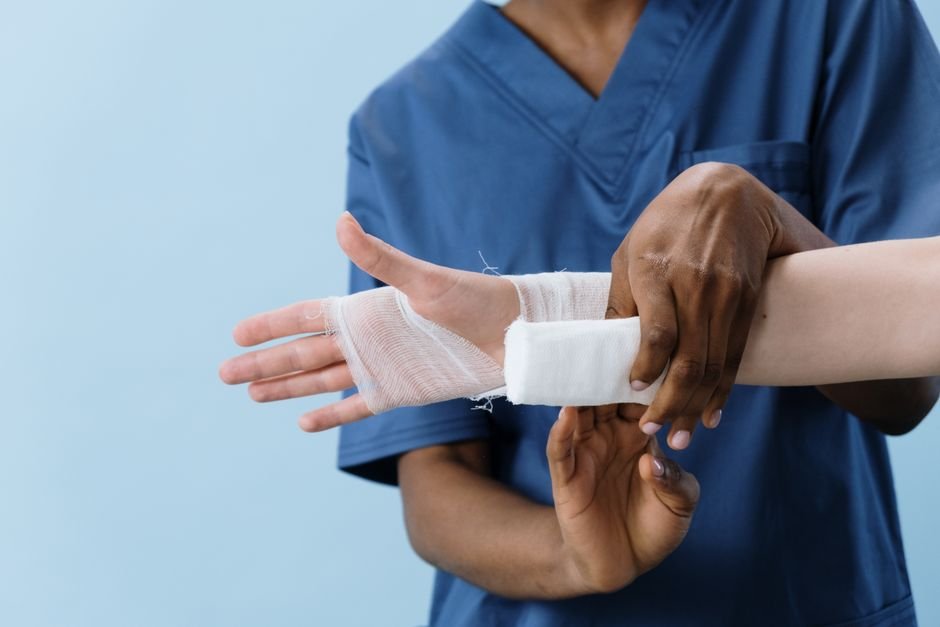 Medical professionals carefully bandaging a patient's hand, demonstrating proper wound care billing practices.