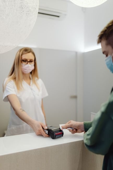 Medical front desk staff assisting a patient with payment processing, vital for laboratory billing.