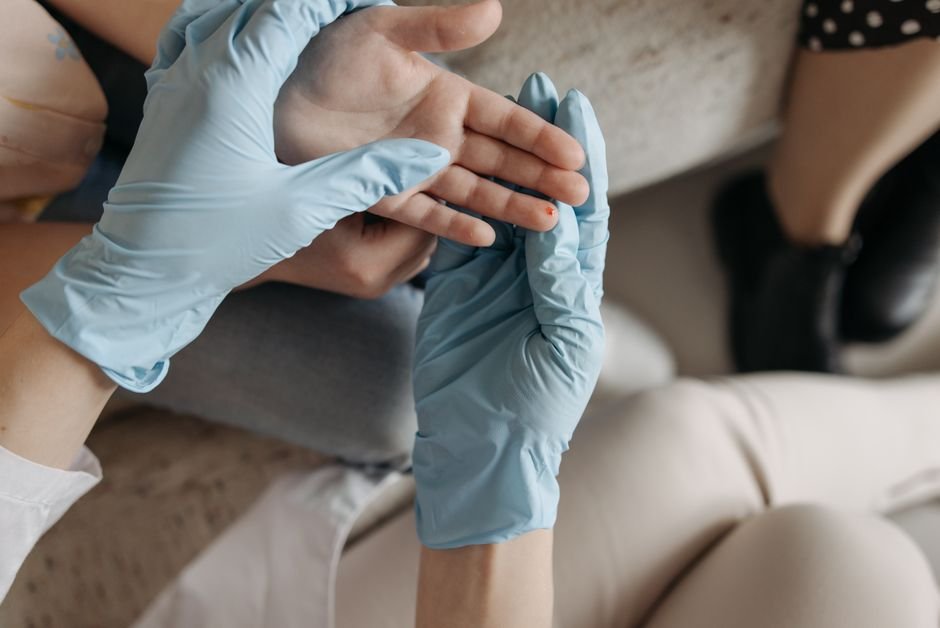 A doctor in blue gloves meticulously examining a small wound, critical for accurate wound care billing.