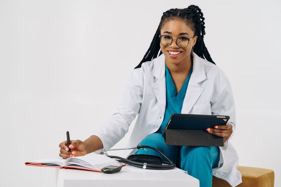 A smiling doctor uses a tablet, engaging with a patient to improve care coordination.