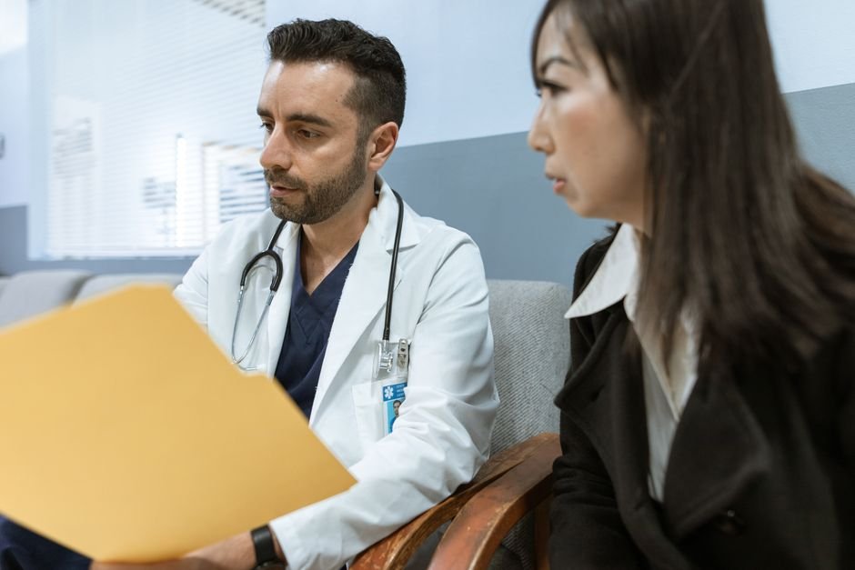 A male doctor discusses discharge plans with a patient at a bedside.
