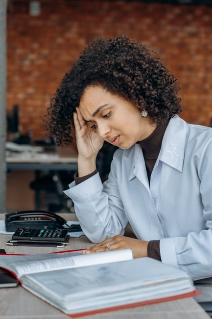 Stressed medical office manager reviewing financial reports, concerned about provider enrollment impacts.